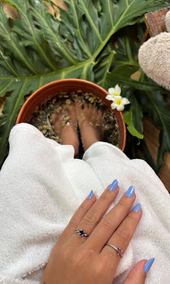 Bacia de escalda pés, com bolo de gude, toalhas brancas e flores amarelas ao lado